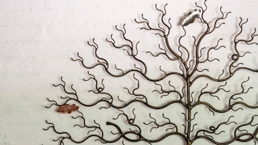 a white brick wall with a metal tree displayed